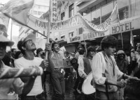 Image of sheet 19860080 photo 7: Transparente Protest Demonstration gegen den Krieg, gegen die Intervention, 1. Mai Demo im Zentrum der Stadt. Mit Musik. Die Kirche hält einen Gottesdienst. Utensilien aus Silber. CTCTR Gewerkschaft. San José de Costa Rica 1986