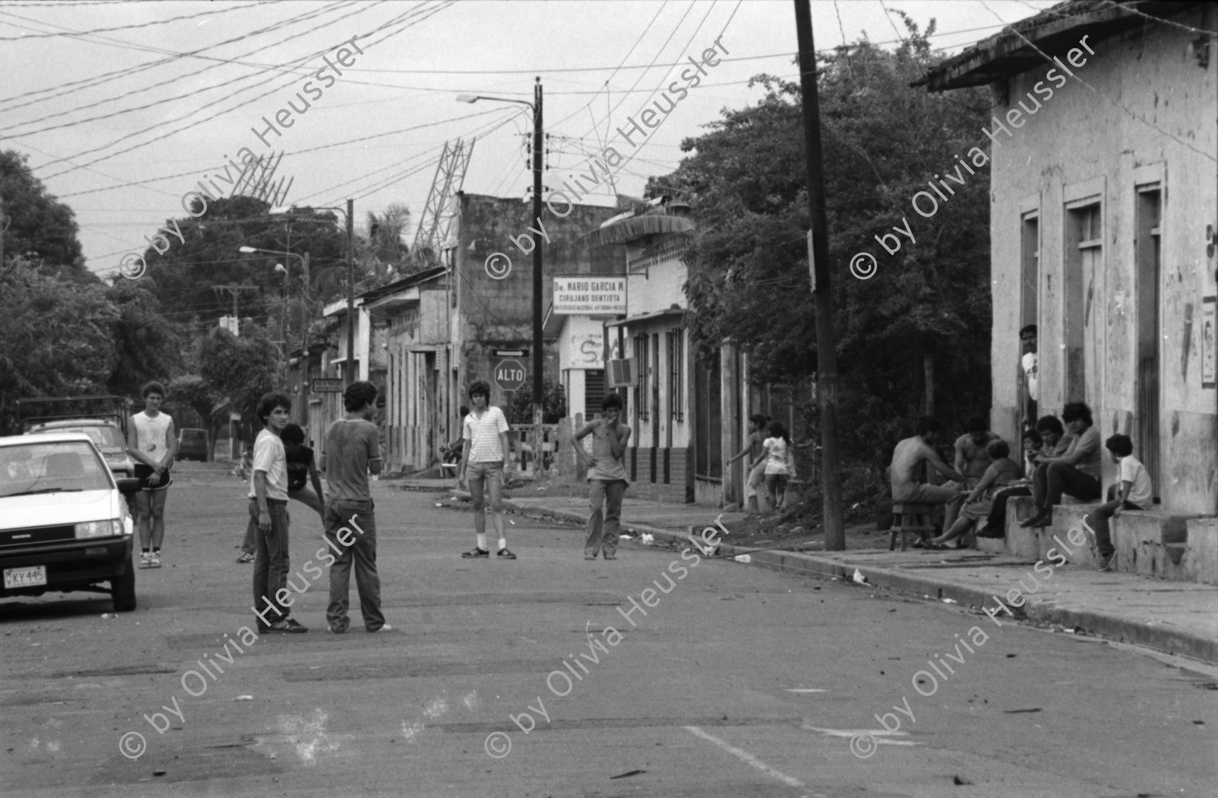 Image of sheet 19860100 photo 32: frtsg. 860090 Soldatinnen für den freiwilligen Militärdienst. Die Familie Quinnonez. José links. in Altagracia. Gruppenbild Familienbild Managua Häuser deren Abschrankung oder Gartenzaun mit ausgedienten Busstüren hergestellt gebaut sind. Wandmalerei Hubstapelfahrerin. typisches Nicaragua Haus.  Fahrzeug in siedlung. Frau spricht mit Mann in Hängematte. Mutter schneidet die Haare ihrer Tochter. Männer spielen Murmel. Hauswand aus Oelfassdeckeln. Betonröhren. Managua 1986