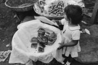 Image of sheet 19870030 photo 29: Dieses kleine Mädchen steht seit Stunden hier und verkauft Brötcben am Markt. Mercado Oriental Managua Nicaragua 1987 √