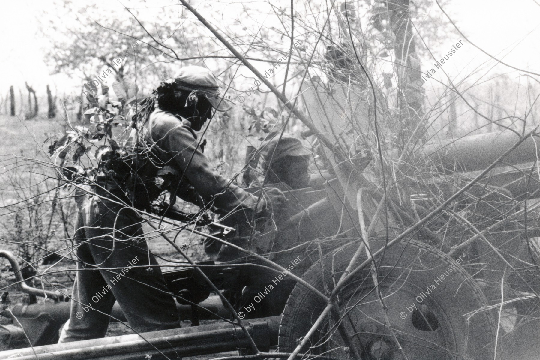 Image of sheet 19870050 photo 27: Ejército Pobular Sandinista EPS  Sandinisten Army Military Miltär Training Manöver in der Nähe des Vulkan Telica in Chinandega. Es ist heiss und staubig. Die getarnten Tarnung Soldaten tarnen sich mit Blätter und Aesten und Infanterie Soldat mit Hanspeter Bürgin. Nicaragua 1987 soldier troops army military eps sandinist central america war training anti tank cannon system soviet mobile 
√ camouflage