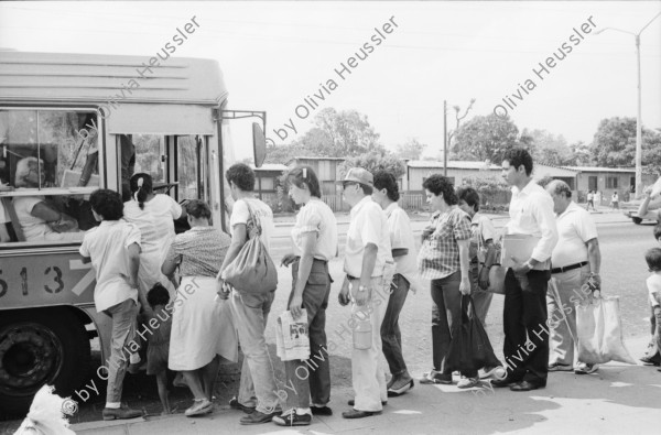 Image of sheet 19870061 photo 16: Bushaltestelle am Mercado R. Huembes. Menschen schleppen und bepacken die Busse. Der Buss fährt nach Masaya. Leute warten auf Buss, ich Olivia heussler spiegle mich im Spiegel des Wartenden. Menschenschlange wartet für den Buss. Managua Nicaragua 1987