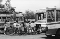 Image of sheet 19870061 photo 7: Bushaltestelle am Mercado R. Huembes. Menschen schleppen und bepacken die Busse. Der Buss fährt nach Masaya. Leute warten auf Buss, ich Olivia heussler spiegle mich im Spiegel des Wartenden. Menschenschlange wartet für den Buss. Managua Nicaragua 1987