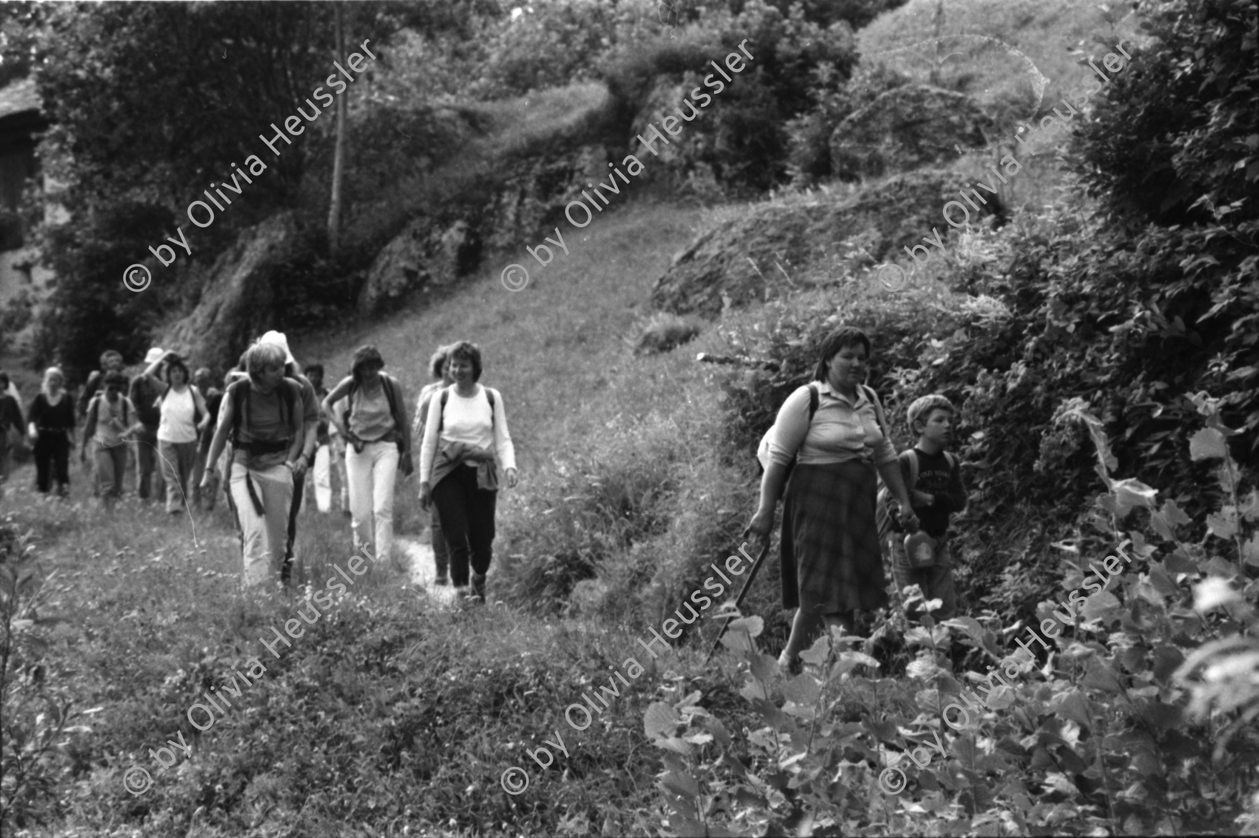 Image of sheet 19870250 photo 15: Frauen Protest Wanderung gegen Staudamm Projekt im Val Madris Kanton Graubünden nach Soglio ins Bergell über 'Bregalia' Pass. Granit Steindächer Berge Uebersicht. Alte Bäuerin auf dem Weg. Frauen Gruppe. Protest im Dorf mit Präsenz von Einwohner. Wald Sterben Waldsterben. Kanton Graubünden 1987 Schweiz