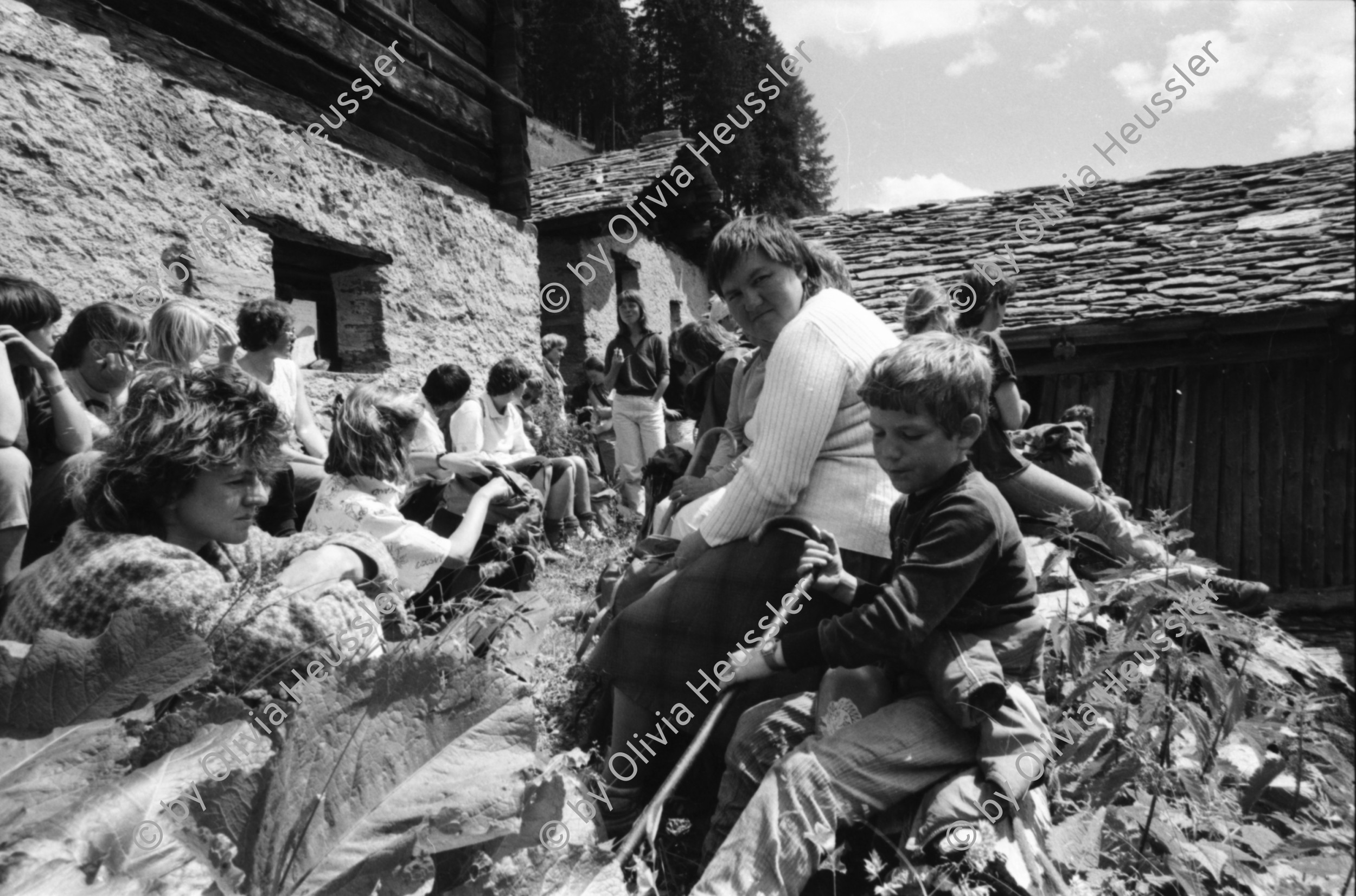Image of sheet 19870250 photo 30: Frauen Protest Wanderung gegen Staudamm Projekt im Val Madris Kanton Graubünden nach Soglio ins Bergell über 'Bregalia' Pass. Granit Steindächer Berge Uebersicht. Alte Bäuerin auf dem Weg. Frauen Gruppe. Protest im Dorf mit Präsenz von Einwohner. Wald Sterben Waldsterben. Kanton Graubünden 1987 Schweiz