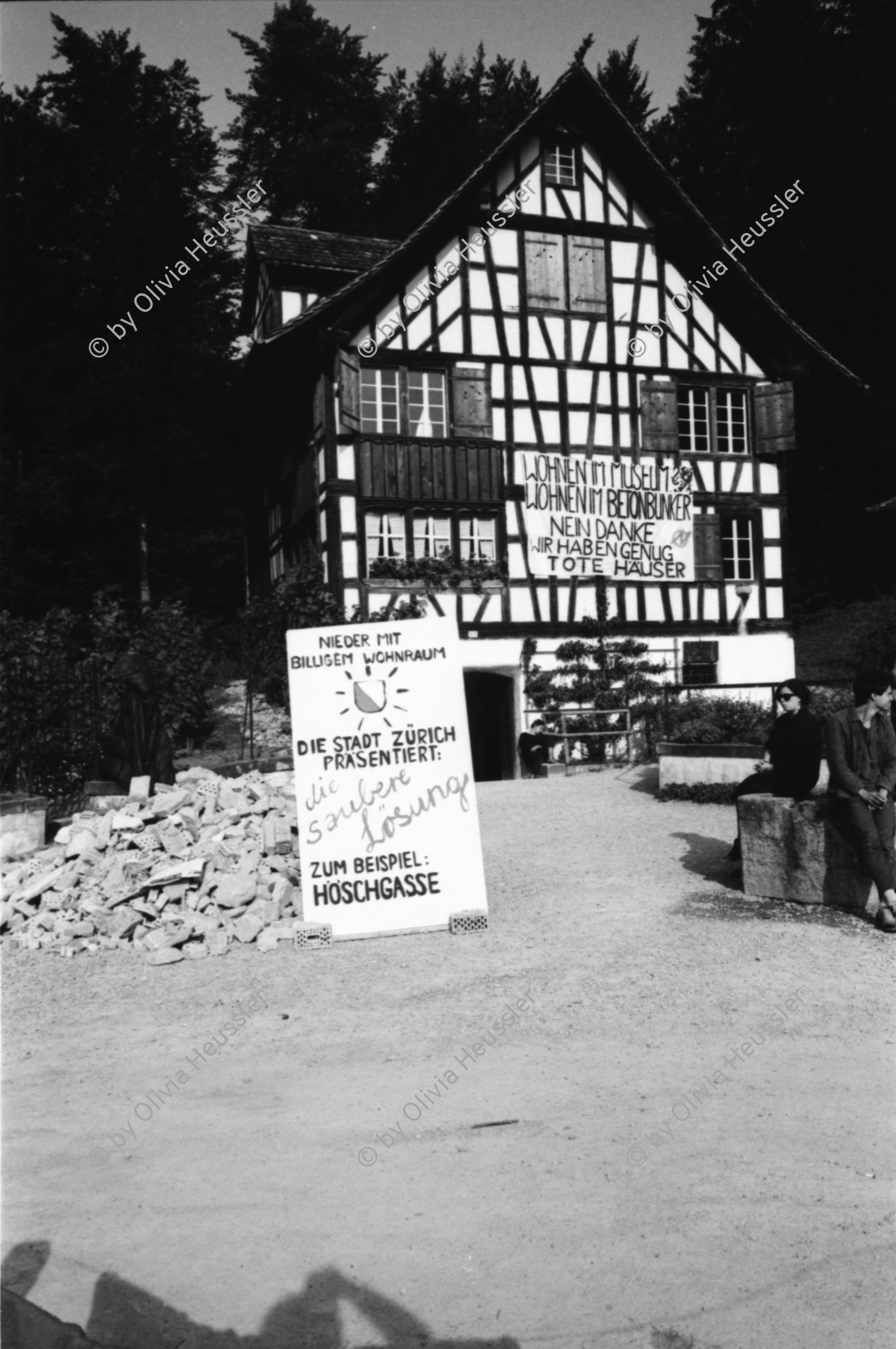 Image of sheet 19870270 photo 19: Besetzung des Freilicht Museums Ballenberg. am Eidg. Bettag. durch Protest Demonstration gegen die Wohnungsnot in Zürich. BesucherInnen in Trachten bestaunen die Transparente. «Die Häuser den Menschen die darin wohnen» Oder:«Die einen sind am Ballen die anderen stehen am Berg» Am Riegelhaus. Olivia nach Weisheits Zahn entfernung. Selbstportrait. 1987 Zürich Bern

Ballenberg is an open air museum in Switzerland that displays traditional buildings and architecture from all over the country. Located near Brienz in the municipality of Hofstetten bei Brienz, Canton of Berne, Ballenberg has over 100 original buildings that have been transported from their original sites