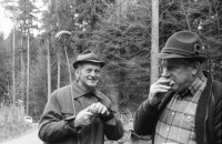 Image of sheet 19880040 photo 33: alter Männer stehen zusammen an Holzgant.Sie schreiben sich die Preise auf. Percy Heussler ist auch dabei. Nr. 12 und 13. Die langen Holz Stiehle zum Cervelats Braten liegen bereit. Die Männer braten Cervelats über dem Feuer. Ein alter Mann zeigt in die Luft. Die Cervelats liegen zum Braten bereit. Die Männer geniessen etwas warmes in der winterlichen Kälte. (!) Holzgant Holzverarbeitung Fällanden Kanton Zürich Schweiz wood forest market man men meat sausage