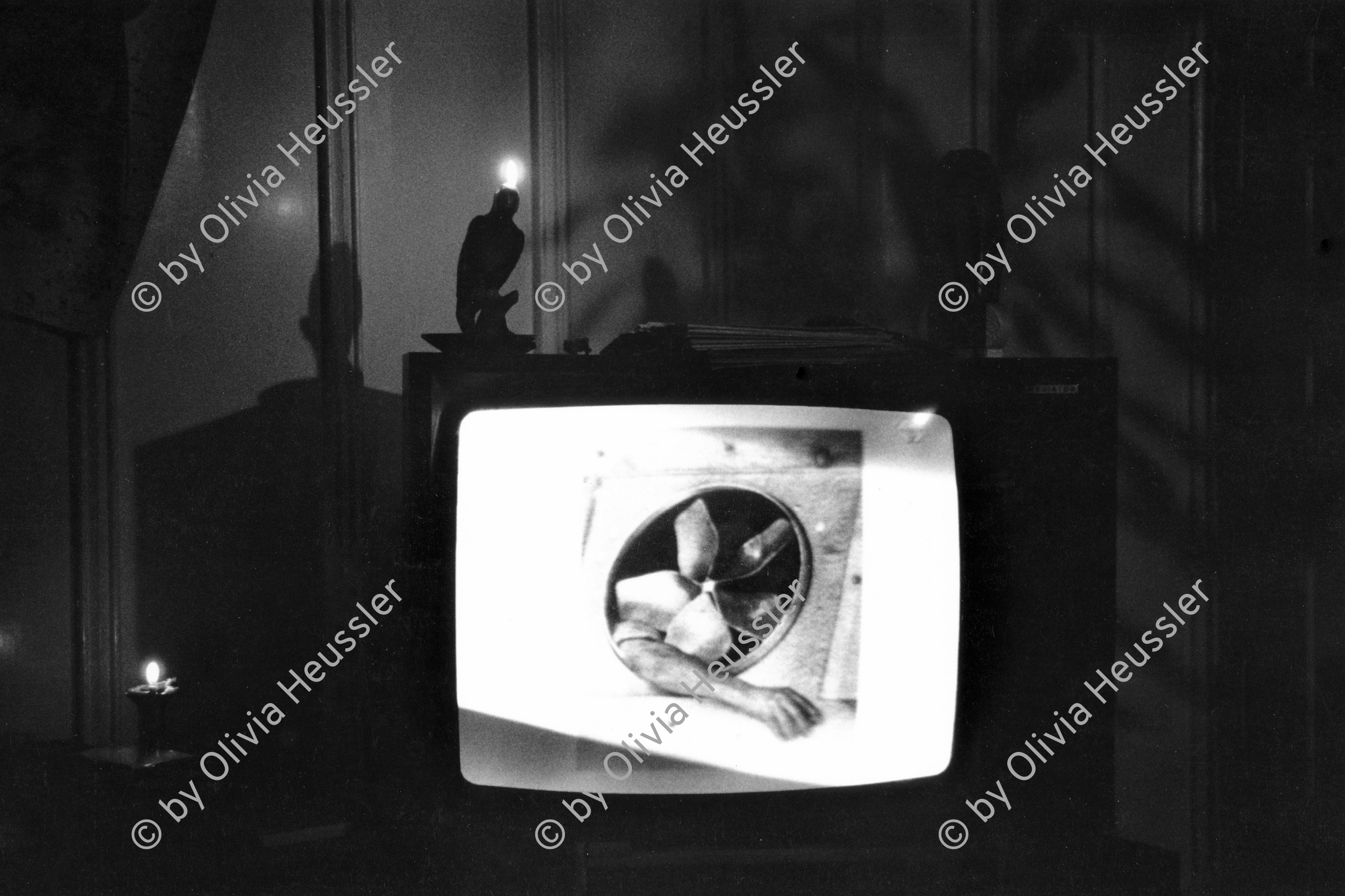 Image of sheet 19880230 photo 31: © 1988, OLIVIA HEUSSLER / WWW.CLIC.LI 
Kertesz fotografiert am TV Television mit brennender Kerze. Zürich 1988 √ 
In meiner Wohnstube in der städtischen Siedlung Erismannhof.  Aussersihl Kreis vier 4 Schweiz Switzerland swiss Schweizer Europe candle arm photography photographer