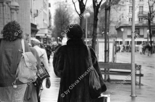 Image of sheet 19880270 photo 18: frstg. 880260        Damen plaisieren vor Schaufenster Damen unter Regenschirmen. Mann mit USA auf dem Rücken. Herren mit Hundchen. gefolgt von einem Hund. in Pelzmäntel an der Zürcher Bahnhofstrasse. Zürich 1988