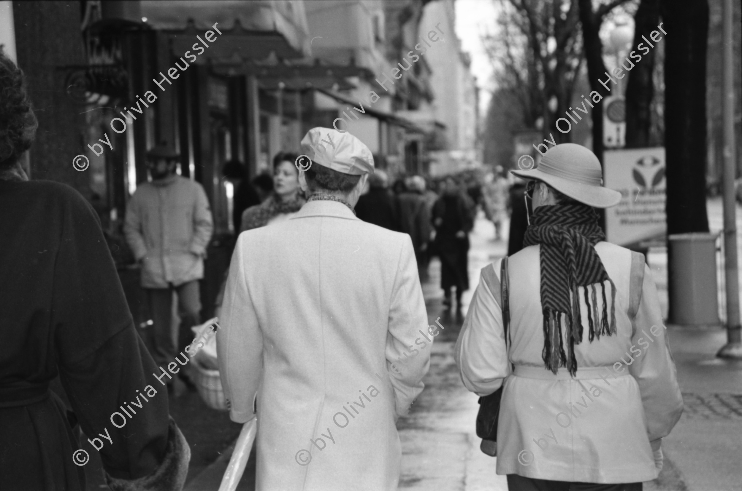 Image of sheet 19880270 photo 25: frstg. 880260        Damen plaisieren vor Schaufenster Damen unter Regenschirmen. Mann mit USA auf dem Rücken. Herren mit Hundchen. gefolgt von einem Hund. in Pelzmäntel an der Zürcher Bahnhofstrasse. Zürich 1988