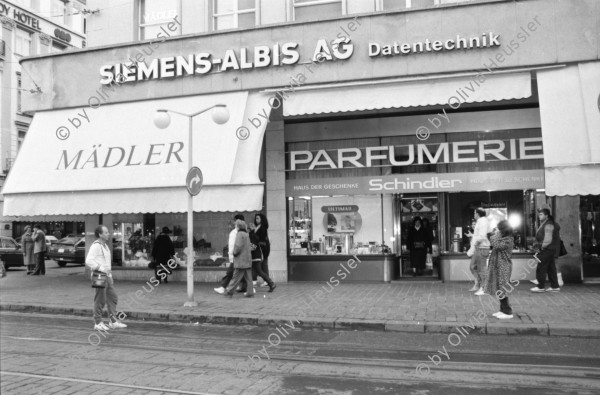 Image of sheet 19880290 photo 15: frtsg. 880280  Filmstreifen Rollen als Dekoration in Migros City Löwenstrasse Junge bestaunen Motorrad. Mann steht an Bahnhofstafel. Bahnhofstrasse 1988 Dame mit Sonnenbrille. Passanten. Vor Hotel beladen Männer Mercedes Benz. Mann und Frau dramatisch im Licht und in Bewegung von unten gehen am Paradeplatz. Bewegungen mit Auto. Frau entsorgt Abfall. Gruppe in Mäntel elegant. Zürich 1988