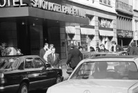 Image of sheet 19880290 photo 18: frtsg. 880280  Filmstreifen Rollen als Dekoration in Migros City Löwenstrasse Junge bestaunen Motorrad. Mann steht an Bahnhofstafel. Bahnhofstrasse 1988 Dame mit Sonnenbrille. Passanten. Vor Hotel beladen Männer Mercedes Benz. Mann und Frau dramatisch im Licht und in Bewegung von unten gehen am Paradeplatz. Bewegungen mit Auto. Frau entsorgt Abfall. Gruppe in Mäntel elegant. Zürich 1988