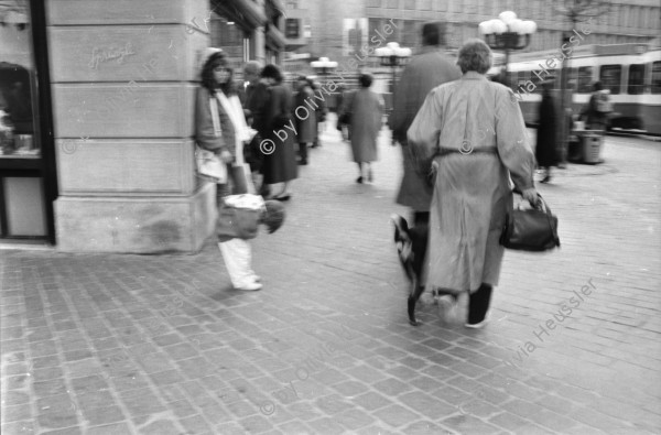 Image of sheet 19880300 photo 1: frtsg. 880290 Pelzmäntel. Geschäftsmann ruht sich aus. Dame in Bewegung. Damen mit Hund. Bei Sprüngli fotografiert ein Tourist mit dickem Bauch Damen vor Reisebüro SBB- Strassenbahn Tram Dame kokettiert. Bewegungen mit Auto. Verkehrs Polizei gibt Busse. Vor Gübelin. Im Regen rennen die Leute über den Paradeplatz. Die Strassenbahn hält. Bahnhofstrasse Zürich 1988