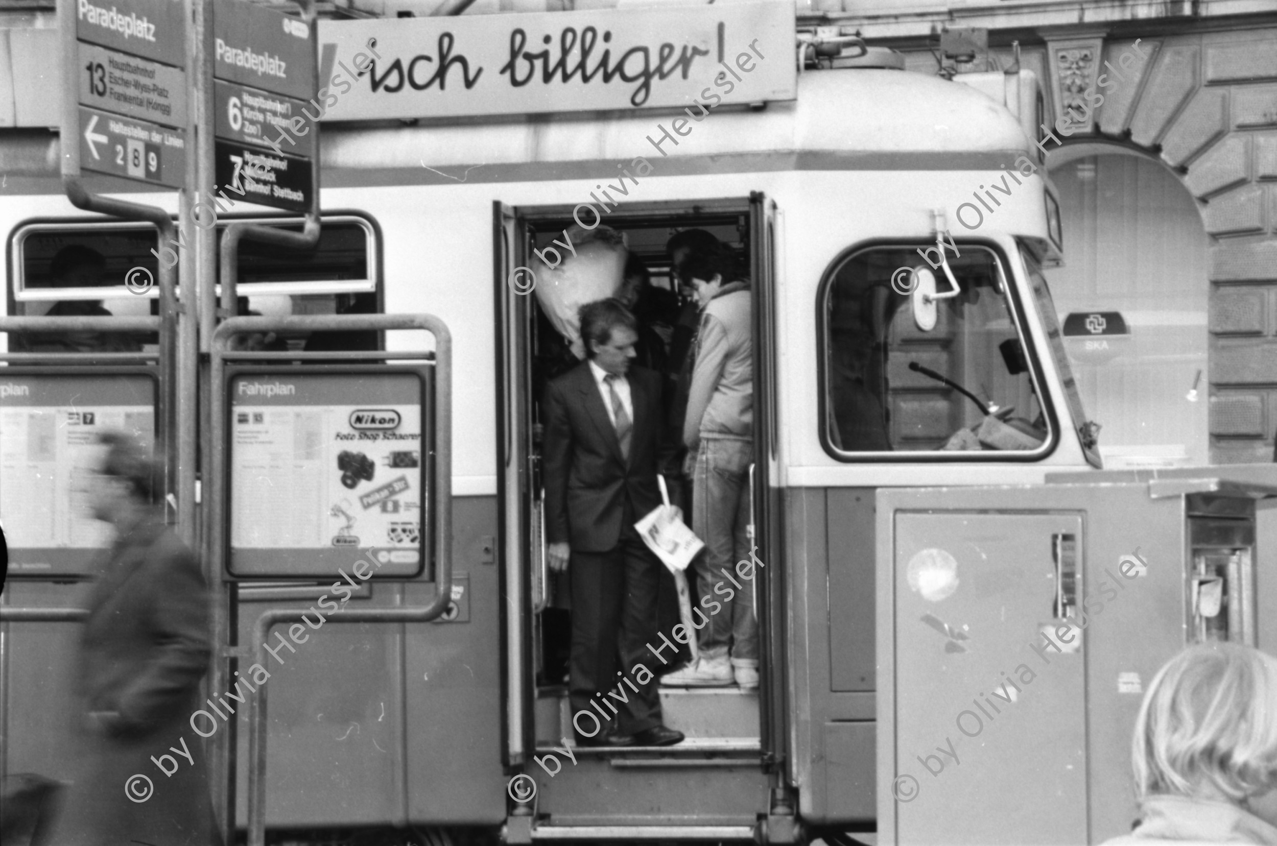 Image of sheet 19880300 photo 13: frtsg. 880290 Pelzmäntel. Geschäftsmann ruht sich aus. Dame in Bewegung. Damen mit Hund. Bei Sprüngli fotografiert ein Tourist mit dickem Bauch Damen vor Reisebüro SBB- Strassenbahn Tram Dame kokettiert. Bewegungen mit Auto. Verkehrs Polizei gibt Busse. Vor Gübelin. Im Regen rennen die Leute über den Paradeplatz. Die Strassenbahn hält. Bahnhofstrasse Zürich 1988