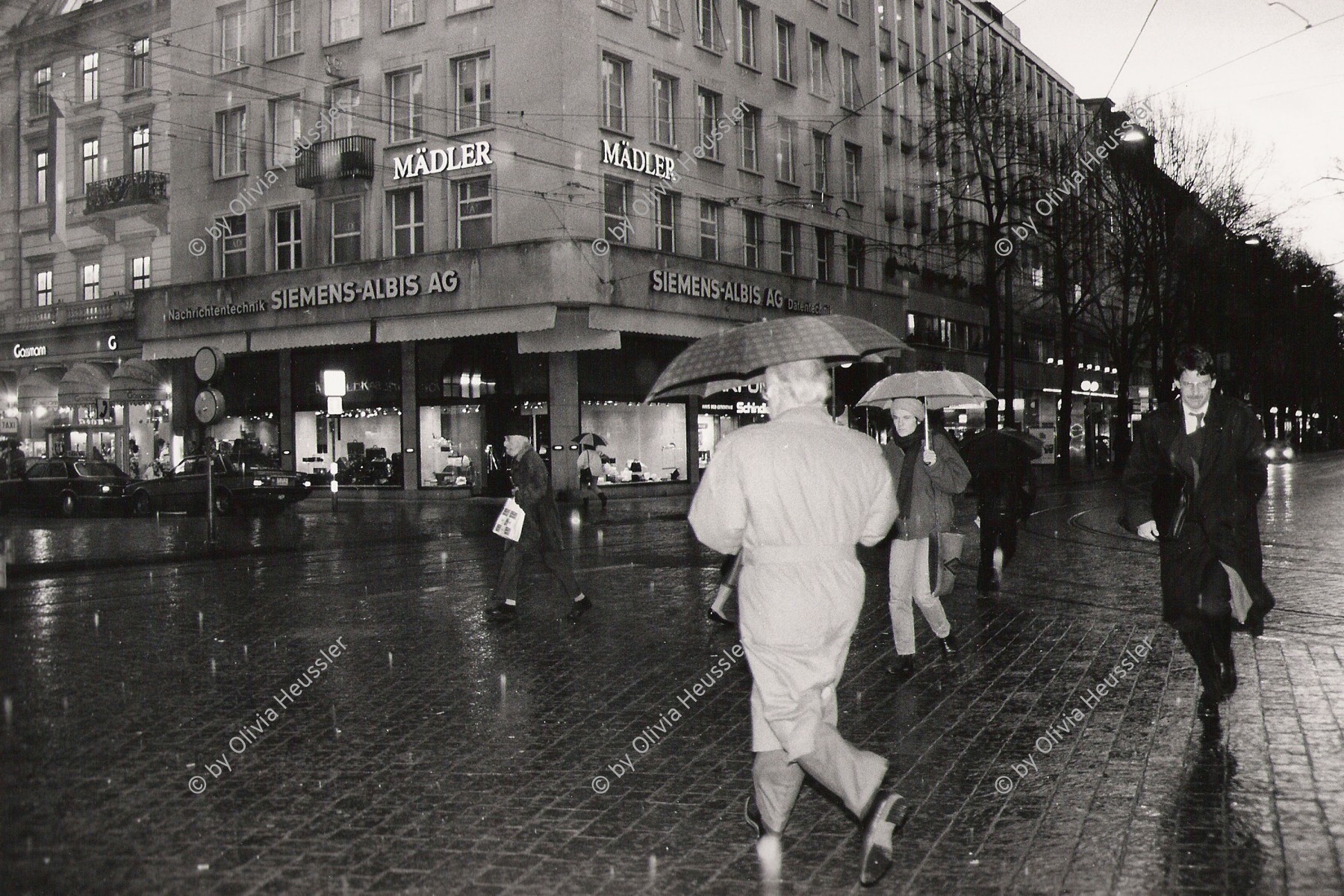 Image of sheet 19880300 photo 31: Im Regen rennen die Leute mit Regenschirm über den Paradeplatz. Bahnhofstrasse Zürich 1988 √
Mädler Albis Siemens Parfumerie Switzerland Swiss Rain