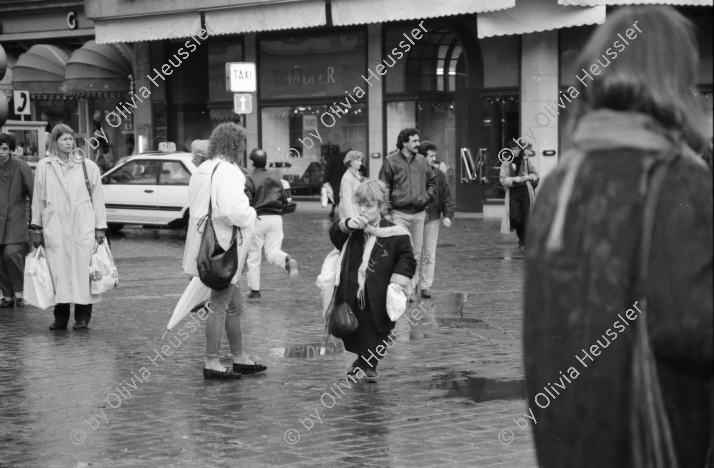 Image of sheet 19880310 photo 30: Bewegung auf dem Paradeplatz an der Zürcher Bahnhofstrasse, es regnet die Menschen rennen gestresst durch den Regen. Unter dem Regenschirm Regenschirmen Bewegung. PassantInnen. Kreis 1 Paradeplatz Zürich 1988 √