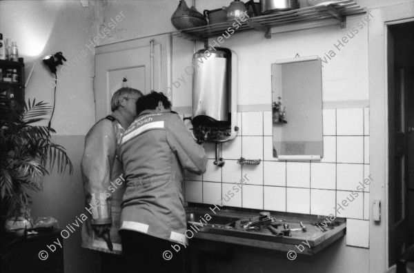 Image of sheet 19880320 photo 1: Die städtische Feuerwehr behebt in der alten Küche im Erismannhof einen Wasserschaden. Koni Nordmann und Felix von Muralt sitzen bei mir in der Küche. Portraits. Olivia Zürich 1988