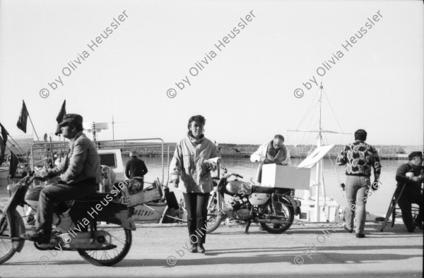 Image of sheet 19880330 photo 32: Plakate mit Frauenfeindlicher Reklame. Im Erismannhof steht Hallo Margrit du schöne Frauen - Wandmalerei. ABB Reklame im Flughafen Zürich. 
In Kreta mit Rudi Berli. Portrait. Frau studiert Todesanzeigen. Plakat der Nea Democratica. Mit Cathy auf dem Boot. mit Costa. Portrait Olivia. Haus typisch. Cathy und Mann X am Strand. Touristen Souvenir auf Autokühlerhaube. Dorf. Xania
Griechenland 1988