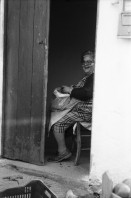Image of sheet 19880350 photo 1: frtsg. 880340 Tassos Mutter Mara Cathy und Tassos Vater im Gewächshaus.  Alte Bäuerin in Schwarz Frauen an Bushaltestelle. Portrait Frau in Busshaltestelle. Am Buss. Meeresbucht von oben. altes Steinhaus. Portrait Daniela Venegoni und Tobias Eugster Hippie. Daniela mit vehülltem Kopf nackt am Strand. Dani und Tobias. Tobias. Gefängnis von Galatas. Mann grilliert Schaf. Kreta Griechenland 1988