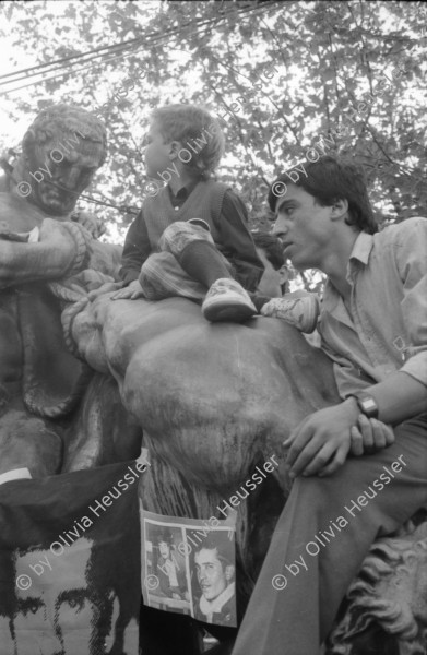 Image of sheet 19880380 photo 11: Iren Stehli und ein Freund. Fest  1. Mai. im Kaserne Innenhof. Mit älteren Besuchern Plakat von kurdischem ermordeten Kämpfer hängt an der Skulptur. Kinderfest Kaserne. Schwarze stehen am Gitterzaun hinter der Kaserne. Kurdische und Türkische AsylantInnen protestieren gegen die Inhaftierung von ihren Genossen. und Kollegen. Sie zünden Petarden an, die sie gegen die Polizeikaserne richten. Fredy Meier. Zürich 1988 Kreis vier Kurds 
Schweiz Switzerland Swiss protest