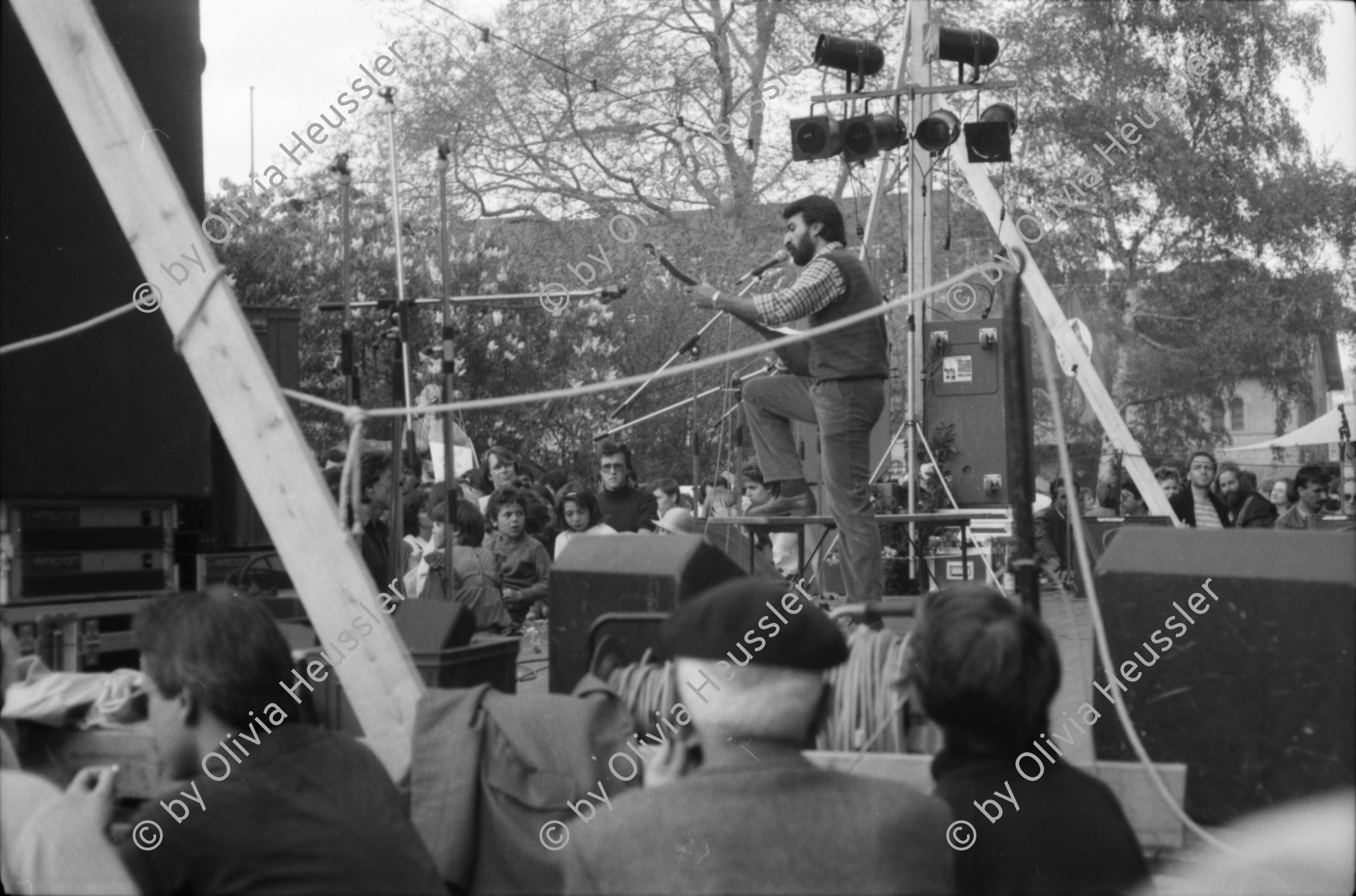 Image of sheet 19880380 photo 14: Iren Stehli und ein Freund. Fest  1. Mai. im Kaserne Innenhof. Mit älteren Besuchern Plakat von kurdischem ermordeten Kämpfer hängt an der Skulptur. Kinderfest Kaserne. Schwarze stehen am Gitterzaun hinter der Kaserne. Kurdische und Türkische AsylantInnen protestieren gegen die Inhaftierung von ihren Genossen. und Kollegen. Sie zünden Petarden an, die sie gegen die Polizeikaserne richten. Fredy Meier. Zürich 1988 Kreis vier Kurds 
Schweiz Switzerland Swiss protest
