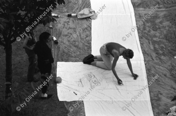 Image of sheet 19880411 photo 1: Susan Büchi malt ein Transparent und Dorothea Hunziker. Wäsche hängt im Erismannhof Innenhof städtische Siedlung Erismannhof Kinder spielen mit Papier Kugeln. 
Die Siedlung vor dem Umbau mit Kinder im Vordergrund.
Zürich 1988