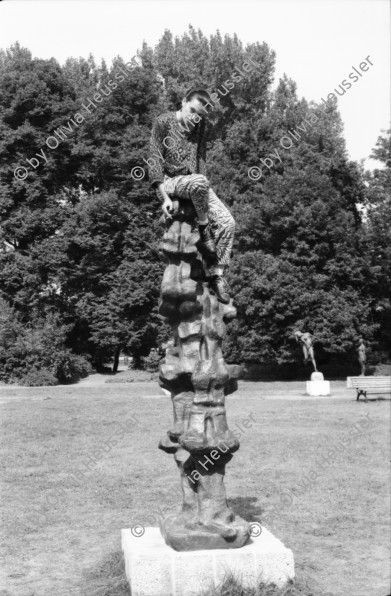 Image of sheet 19880691 photo 18: Ausstellung Walter Martin Plakat Kunst Bildhauerei Plastik wird von Leuten besucht. Yasmina, die Tochter von Christiane Barckhausen Canale sitzt auf einer Plastik. Figur. Das Konzerthaus in Berlin wird renoviert. An der Schutzwand während der Bauerei hängen Plakate wie sie aussehen soll. Ein spritzt lange Treppe mit Wasser ab. Vor einem Laden stehen Holzharasse. Gunhild Brandler verdeckt sich das Gesicht. Unter dem Titel 'Lieber Sonne im Herzen' organisiert die FDJ Freie Deutsche Jugend den diesjährigen Liedersommer auf der Insel der Jugend. Eine junge blonde FDJ lerin sitzt  mit Netzstrümpfen da. Ihr Genosse will nicht das ich sie fotografiere und macht sich springbereit. Uebersicht auf das Zelt. Da steht eine  Plastik. Berlin Ost Deutschland 1988