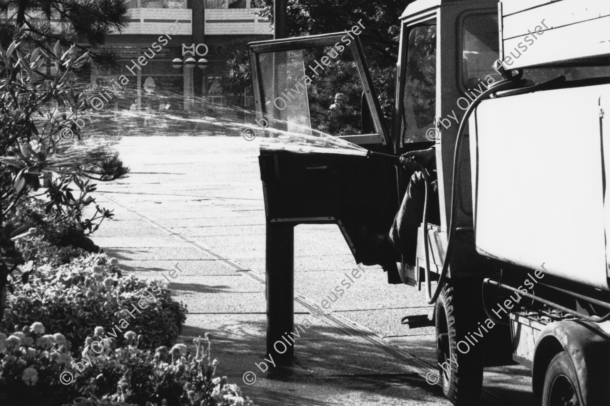 Image of sheet 19880693 photo 36: Der Mann sitzt im Gefährt und hält den Wasser Schlauch aus dem fahrenden Tankwagen. Besprühen von Garten Pflanzen anlagen. Alexanderplatz Berlin GDR DDR Deutschland Ost Ostdeutschland Ostberlin 1988 √