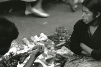 Image of sheet 19880990 photo 8: Ein Junge interessiert sich bei einer Marktfrau für eine Spielzeugwaffe Pistole Guatemala City 1988 √ Am Markt Stand