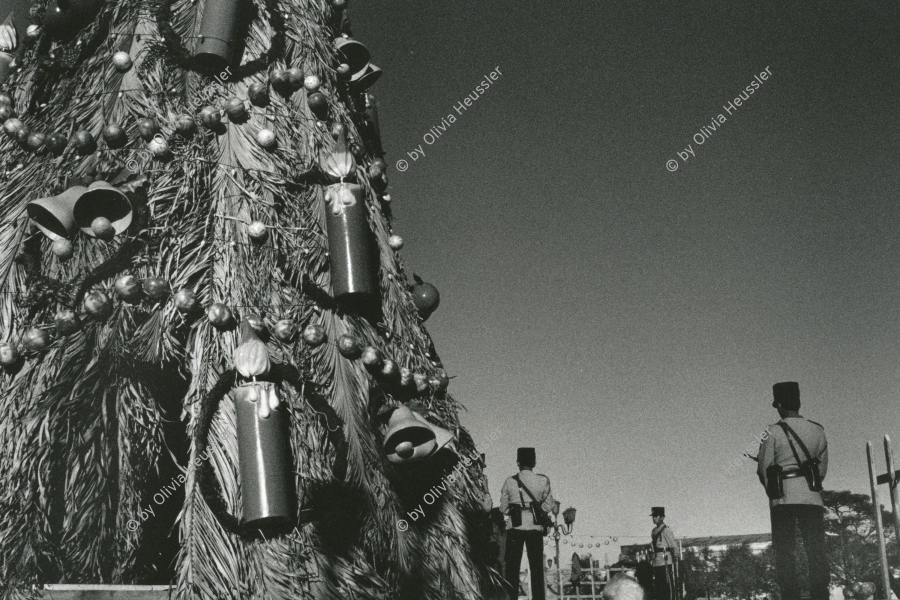 Image of sheet 19881000 photo 26: © 1988, olivia heussler /www.clic.li
Während den vorweihnächtlichen Zeremonien Mit Weihnachtsbaum von Soldaten bewacht, auf dem Regierungs platz Plaza de Gobierno in Guatemala City. 12.88 1988 √ christmas tree huge police soldier candles Weihnachten 

im Besitz von: Banco del Gottardo Chiasso 
Out of: From time to time  / Von Zeit zu Zeit
Exhibition

copyright by Olivia Heussler