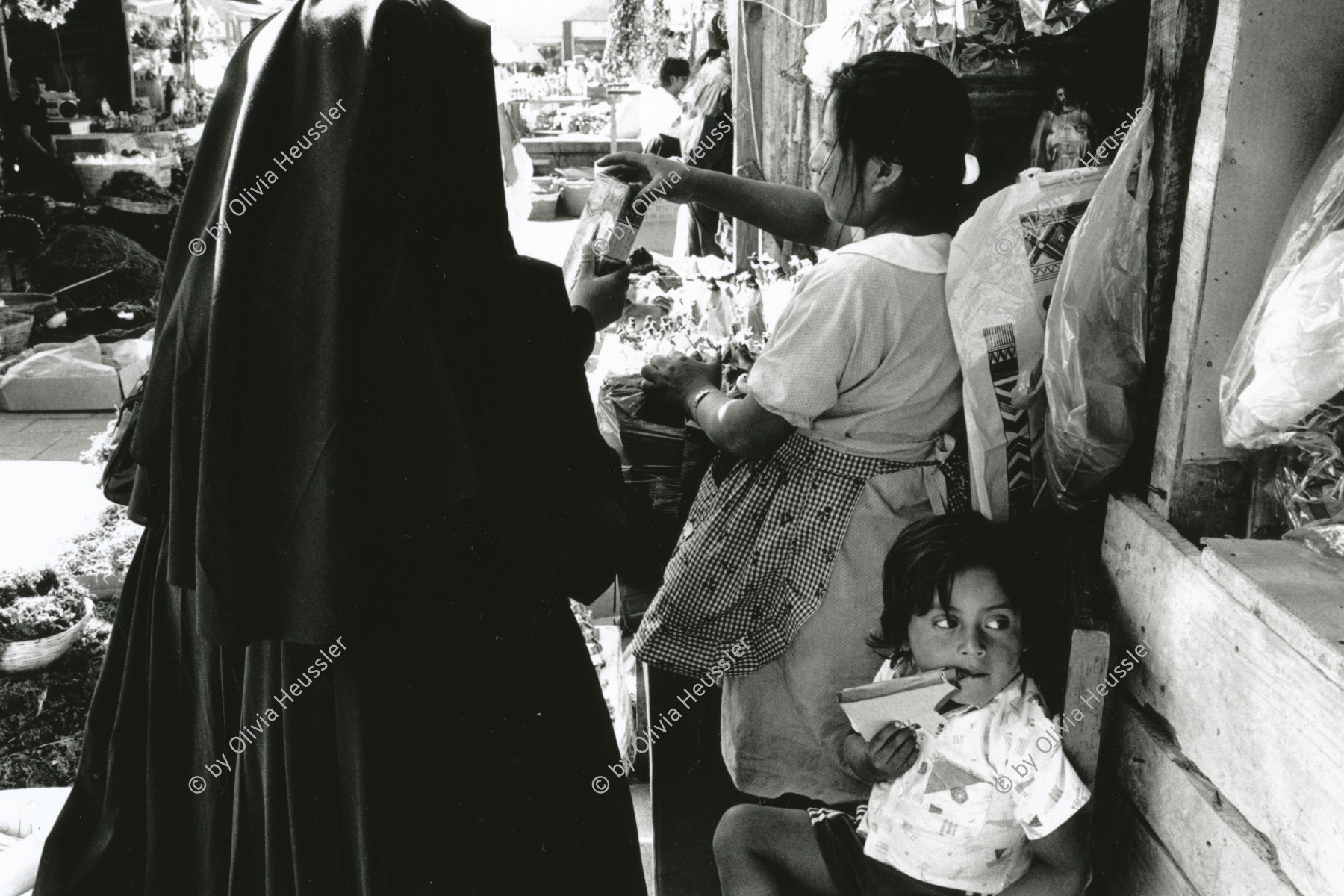 Image of sheet 19881010 photo 32: Strassenkind mit spielzeugpistole im Mund und Nonne am Markt. Marktszenen. Guatemala City 1988 √