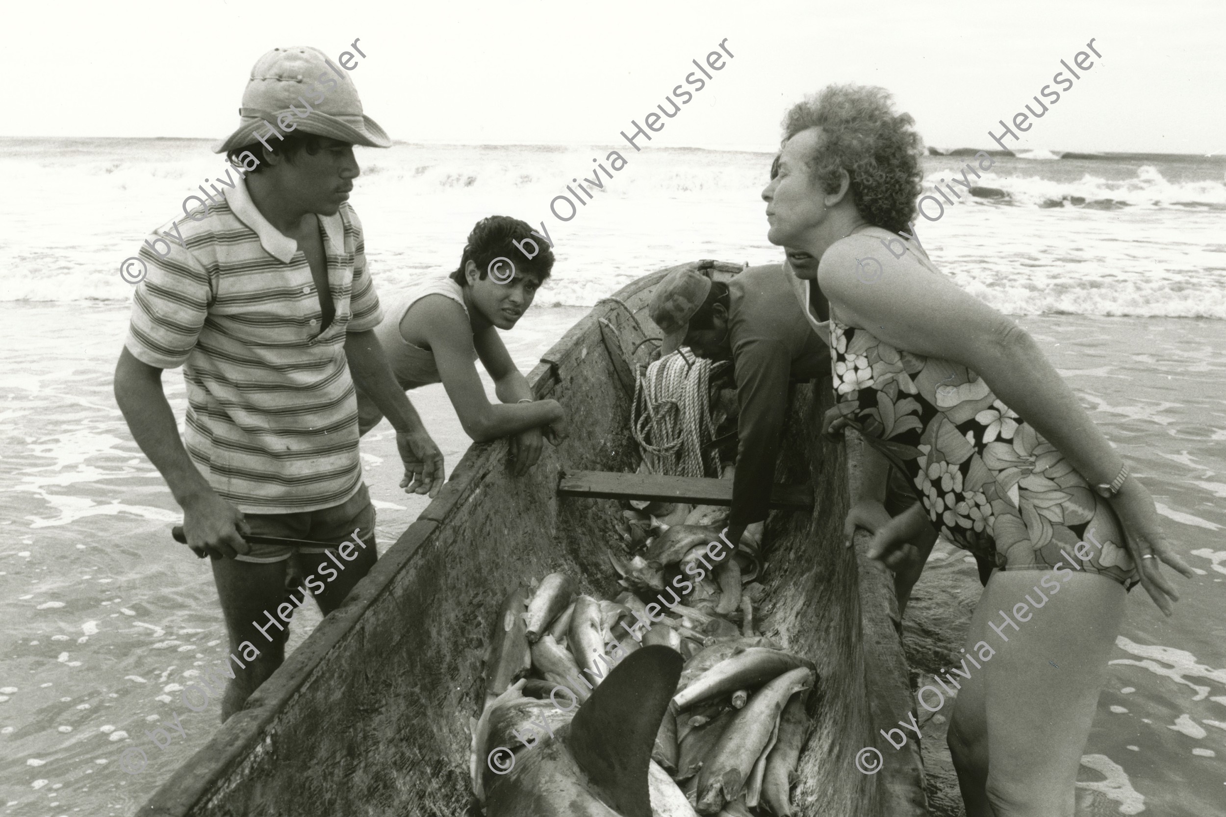 Image of sheet 19881080 photo 29: Eine Touristin erkundigt sich bei den Fischern um ihre Beute. Einem Haifisch, dem die Flossen bereits abgetrennt wurden. Fischmarkt Export. Nicaragua 1988 √