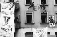 Image of sheet 19890280 photo 6: frtsg. 890270 Demo Wohnen tut Not. Ankerstrasse 124 mit Transparent SpeckulAir. Entieeignet. falsch geschrieben steht an der Hausmauer. frisch gemalt. Von Männern die sich der Hausfassade entlang abseilten. Spray Graffitti Zürich 1989 Wohnungsnot