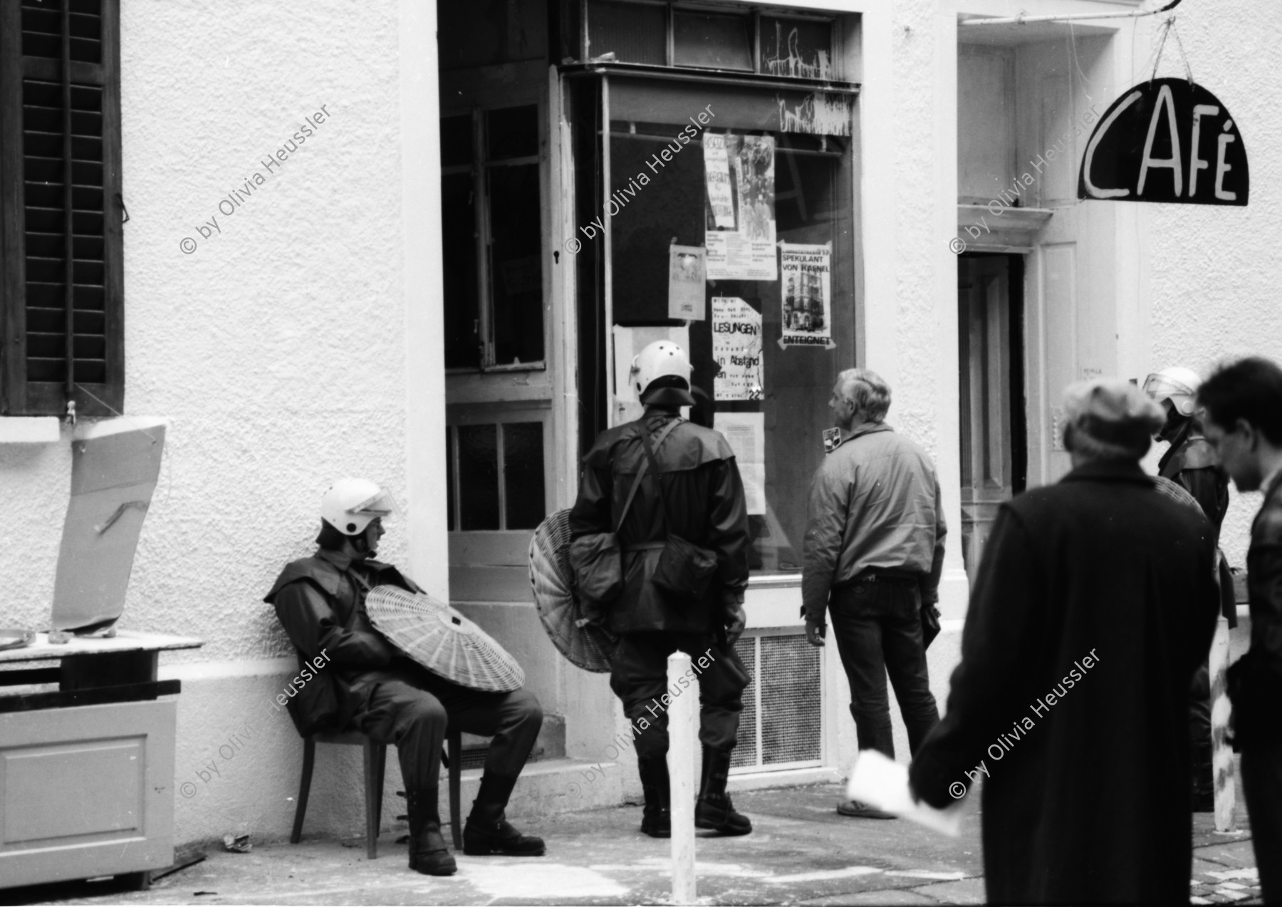 Image of sheet 19890330 photo 10: Polizei-Grendadier mit Korbschild auf einem Stuhl vor besetztem Café, Zürich 1989. Kreis 4 Aussersihl
wohnungsnot