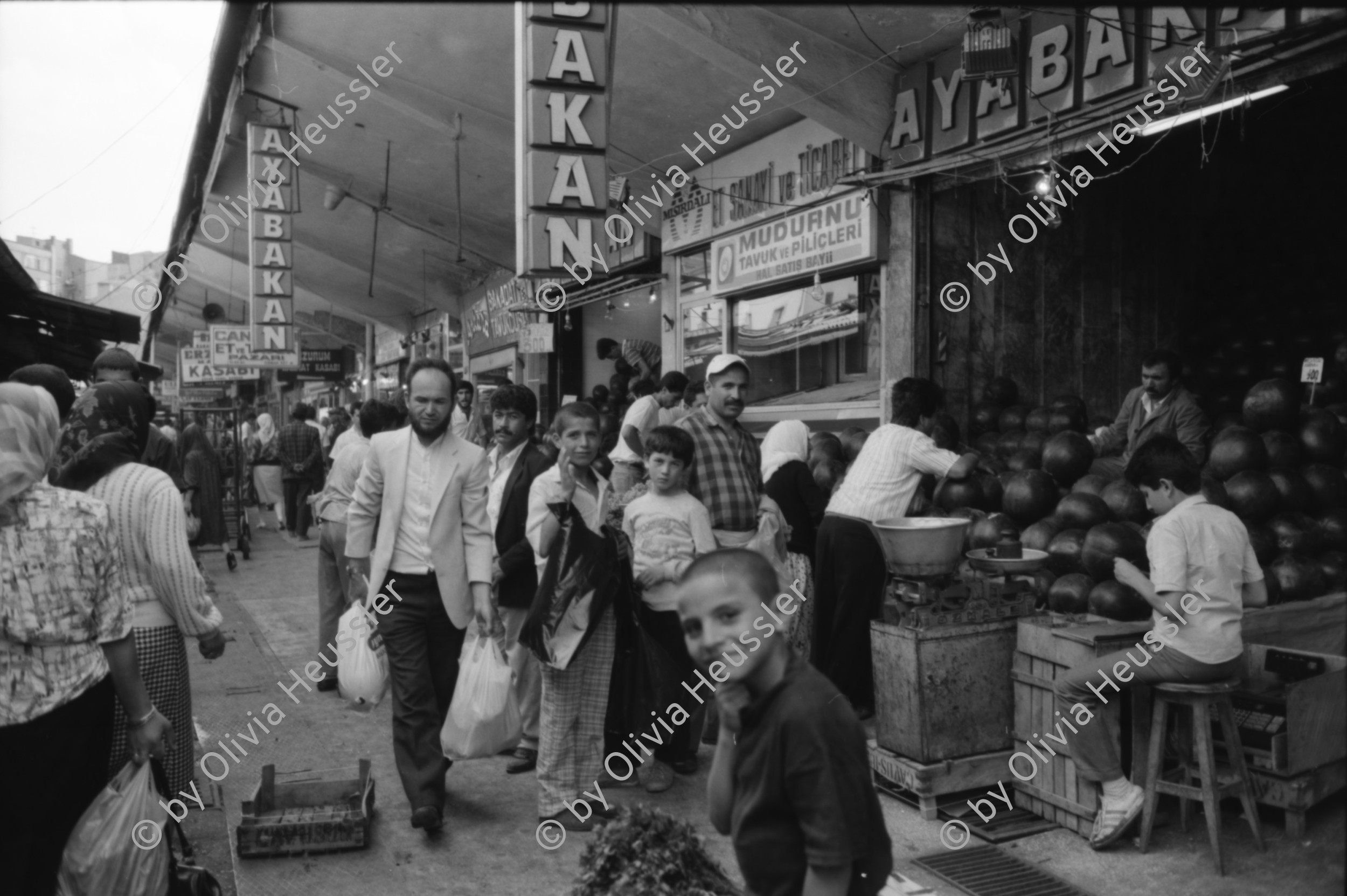 Image of sheet 19890540 photo 31: Moschee Kocatepe Schuhe stehen draussen (Tagi). Melonen stehen wie Kanonenkugeln vor der Moschee. Mann vor Kinoreklame mit Totenkopf. Umzug. Möbel steht auf der Strasse mit eingebautem Spiegel. Treppe zur Altstadt. Mann sitzt Frau arbeitet. Kale Ankara Türkisches Haus. Innenhof. Wolle wird zum trocknen aufgehängt. Uebersicht. Kinder. Frauen arbeiten mit Wolle. Frauen und Kinder kommen entgegen. Mercedes Benz. Innenstadt. Soldat sitzt in Kaffee. Männer essen am Markt. Marktszene. Innestadt Altstadt. Mann. Türkei Ankara 1989