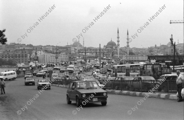 Image of sheet 19890580 photo 11: In der Istanbuler Innenstadt bettelt eine Frau mit ihrem Kleinkind auf dem Arm. Szene Altstadt 'OERLIKON'. Zwei Männer. Alte. Personen. Strassenhändler verkauft Bretzeln Polizei. Strasse und Verkehr.  Galatas Brücke Maja Wicki und Leman Firtina. Unter der Brücke gibt es schöne kleine Fischrestaurants im Hintergrund eine Moschee. Messerschleifer. Alte Frau. Istanbuler Bahnhof Denkmal. Polizei. Personen. Nikon Reklame. Leman im Büro des Menschenrechtsverein, mit einem Vater eines Gefangenen. Istanbul Turkei Türkei Turkey 1989