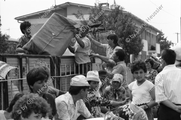 Image of sheet 19890600 photo 37: 34. Tag des Exodus türkischstämmiger Flüchtlinge aus Bulgarien, Kapikule Türkei 1989.

Deportierte in der Türkei. Lastwagenschlage an der Türkisch-Bulgarischen Grenze. Auf dem Bahn-Quai von Kapikule sitzen und liegen hunderte von Türkischstämmigen BulgarInnen mit ihren Familien erschöpft in einem grossen elenden Durcheinander. Die Türkische Fahne bedeutet für viele das Symbol eines 'freien' Landes. In Bulgarien hat man sie gezwungen ihre Namen und ihre Sprache zu ändern. Oezal benützt die ca 300'000 Bulgaren für seine Wahlkampagne. Viele Kinder weinen unaufhörlich vor Erschöpfung. In Bergen von Hab und Gut entdecke ich ganze Wohnungseinrichtungen. Der Duty Free Laden ist geschlossen. Die Güterwagen, in denen die Menschen tagelang eingesperrt reisen mussten, werden nach ihrer Leerung wieder zurückfahren und noch mehr Familien in ihr Unglück stürzen. Türkei Turkey Bulgarian Refugees 1989