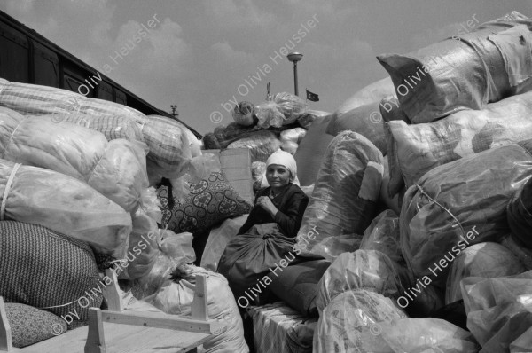 Image of sheet 19890620 photo 11: frtsg. 890600  Auf dem Bahnsteig von Kapikule entdecke ich immer wieder zwischen Sack und Pack vereinsamte Menschen im Elend. Hab und Gut. Einwanderungsbüro. Türkische Fahne. Eine Hand zeigt auf den leeren Güterwagen, wo nicht nur Hausrat transportiert wird, sondern Menschen über 10 Stunden ohne Frischluft und Wasser reisen. Türkei Kapikule 1989 Exhibition