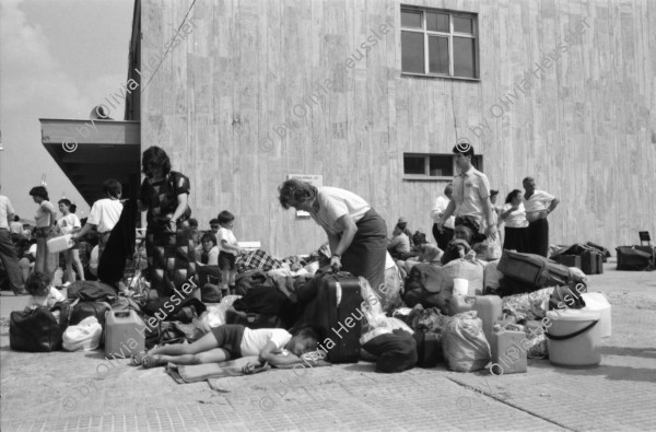 Image of sheet 19890620 photo 26: Auf dem Bahnsteig von Kapikule entdecke ich immer wieder zwischen Sack und Pack vereinsamte Menschen im Elend. Hab und Gut. Einwanderungsbüro. Türkische Fahne. Eine Hand zeigt auf den leeren Güterwagen, wo nicht nur Hausrat transportiert wird, sondern Menschen über 10 Stunden ohne Frischluft und Wasser reisen. Türkei Kapikule 1989