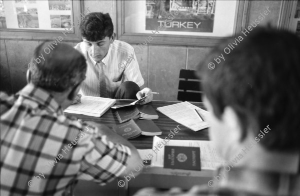 Image of sheet 19890620 photo 30: Auf dem Bahnsteig von Kapikule entdecke ich immer wieder zwischen Sack und Pack vereinsamte Menschen im Elend. Hab und Gut. Einwanderungsbüro. Türkische Fahne. Eine Hand zeigt auf den leeren Güterwagen, wo nicht nur Hausrat transportiert wird, sondern Menschen über 10 Stunden ohne Frischluft und Wasser reisen. Türkei Kapikule 1989