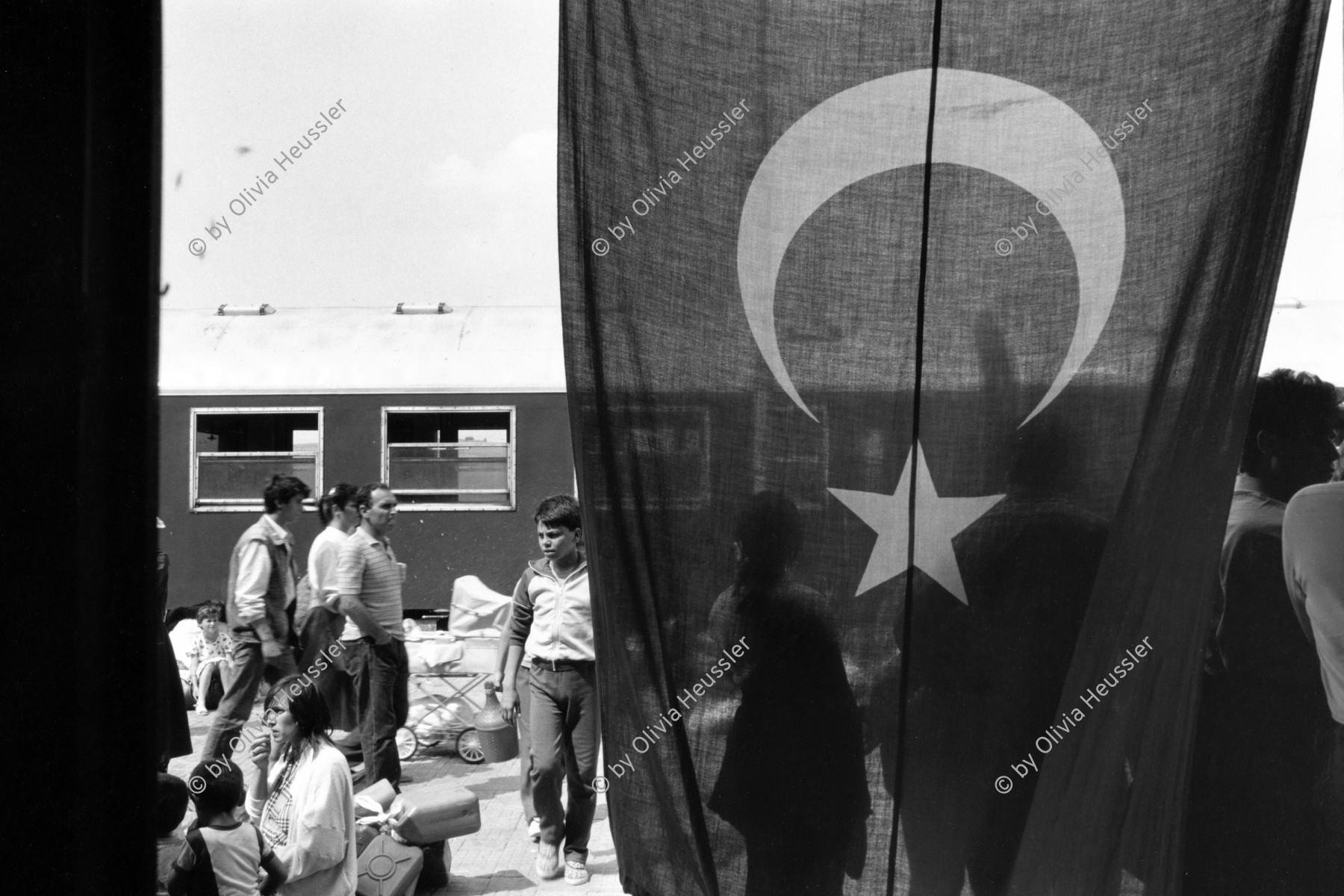 Image of sheet 19890620 photo 32: Türkischstämmige Bulgaren nach der Ankunft auf dem Bahnhof in Kapikule. Türkische Flagge flag Fahne. mit dem türkischen Halbmond. Turkey Türkei 07.89 Refugees Flüchtlinge 1989 

Nach der Ankunft auf dem Bahnhof in Kapikule
ein türkisch stämmiger Bulgare auf dem perron railroad station den Eisenbahnwagen indem er aus Bulgarien geflohen ist. Türkei 07.89 1989 √
refugees from Bulgaria at the train waggon cars railroad in wich he fled to Turkey. Most of the 300 000 refugees have later returned to Bulgaria becose of lack of work in Turkey.