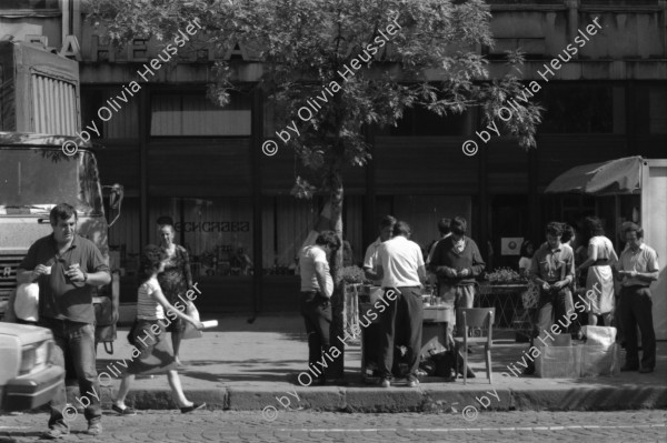 Image of sheet 19890651 photo 9: Ein türkischstämmiges Ehepaar piknikt in einem Restaurant! zwei Frauen betrachten eine Bluse. Mann schläft in Lada. Maja Wicki überquert Strasse. Szenen in der Altstadt und Einkaufsstrasse. Altes Bauernehepaar verkauf Gemüse. Schatten von Maja. Alter Mann mit Matrosenmütze. Mutter mit Kleinkind am Busen. Kindergruppe macht Ausflug und kämpft sich über Pfütze. Mahlzeit! In Volksküche. Unfertige Fussgängerpassage. Hauptplatz. Sofia Bulgaria Bulgarien 1989