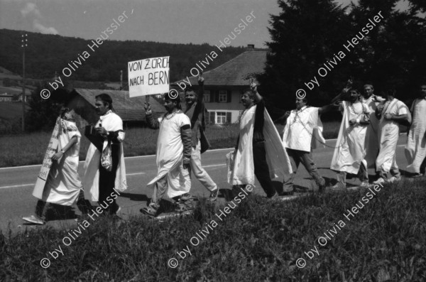 Image of sheet 19890700 photo 14: 20 Kurden gehen in einem Protestmarsch von Zürich nach Bern zu Fuss. Protest gegen die Ausschaffungspolitik der Schweizer Regierungen. Die ländliche Bevölkerung hat kein Interesse an der Informationen der Kurden. Sie warten auf ein Radfahrer Velorennen rennen. In einer Badeanstalt. Dicker fetter Mann mit glanz auf der Brust in Badehose im Schwimmbad. Bäbe Weber und Pierre Mennel tanzen auf dem 'Felde'.