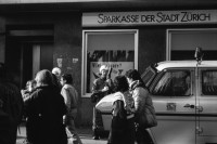 Image of sheet 19890820 photo 19: Thomas Kern liegend. Catherine Boss spricht an Antifa Demo. Raffi mit Faschos nein Danke auf Wange gemalt. Gegen Rassismus. Beamte Polizei Grenadiere. Schönes Licht in der Langstrasse. Polizei schützt Demonstration Protest von Angriffen einer Gruppe Skin Heads. Zürich Aussersihl Kreis 4 1989
