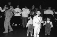 Image of sheet 19890860 photo 19: Demonstration im Kasernen Innenhof. Modepuppe sitzt an Nähmaschine im Freien. In einem Lebensmittelladen für TürkInnen. Asyl bewerber Innen. Uniformen hängen da, während Männer essen. Zwei Frauen stehen da. Unbekannte Gestalt beim Telefonieren in Telefon Kabine. Schliessung eines Ladens. Zwei Männer als Türkisches Beschneidung fest in einer Turnhalle in Pratteln. Frauen und Kinder und Männer tanzen zusmmen . Basel Brauchtum turkish boy circumcision child tradition muslim religion asylum seekers human rights Switzerland Schweiz 1989
