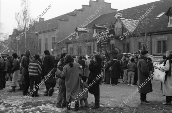 Image of sheet 19890860 photo 3: Demonstration im Kasernen Innenhof. Modepuppe sitzt an Nähmaschine im Freien. In einem Lebensmittelladen für TürkInnen. Asyl bewerber Innen. Uniformen hängen da, während Männer essen. Zwei Frauen stehen da. Unbekannte Gestalt beim Telefonieren in Telefon Kabine. Schliessung eines Ladens. Zwei Männer als Türkisches Beschneidung fest in einer Turnhalle in Pratteln. Frauen und Kinder und Männer tanzen zusmmen . Basel Brauchtum turkish boy circumcision child tradition muslim religion asylum seekers human rights Switzerland Schweiz 1989