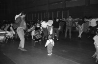 Image of sheet 19890870 photo 0: frtsg. 890860 Türkisches Beschneidungs ritual fest in einer Turnhalle in Pratteln. Frauen und Männer und Kinder tanzen. Ein Mädchen führt die Gruppe mit einem weissen Taschentuch. Zwei alte Männer sitzen neben dem kleinen Jungen in Uniform. Bild mit seiner Familie. Priska Fetz von Aarau tanzt auch mit. Familiengruppenbild. Kanton Baselland 1989  Schweiz Turkey Türkei Refugees Flüchtlinge Boy circumcision