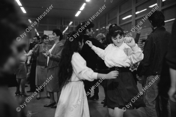 Image of sheet 19890870 photo 22: frtsg. 890860 Türkisches Beschneidungs ritual fest in einer Turnhalle in Pratteln. Frauen und Männer und Kinder tanzen. Ein Mädchen führt die Gruppe mit einem weissen Taschentuch. Zwei alte Männer sitzen neben dem kleinen Jungen in Uniform. Bild mit seiner Familie. Priska Fetz von Aarau tanzt auch mit. Familiengruppenbild. Kanton Baselland 1989  Schweiz Turkey Türkei Refugees Flüchtlinge Boy circumcision