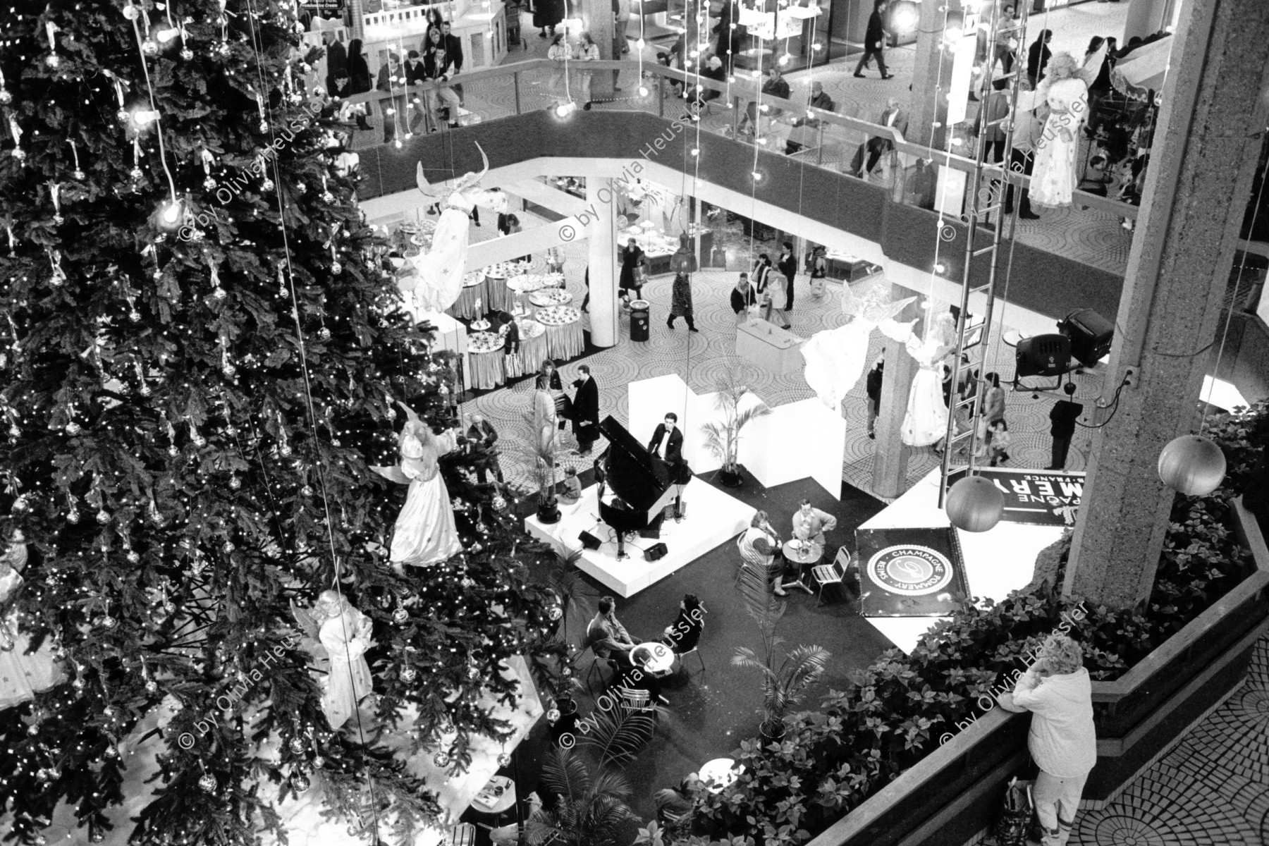 Image of sheet 19890900 photo 13: Der Weihnachtsverkauf im Einkaufszentrum Glatt ist in vollem Gange. Zürich, 1989 √ Schweiz Switzerland Swiss publicity shoping mall center cristmas christmas time tree woman lonelyness piano player klavier musiker music concert open space winter lights lamps