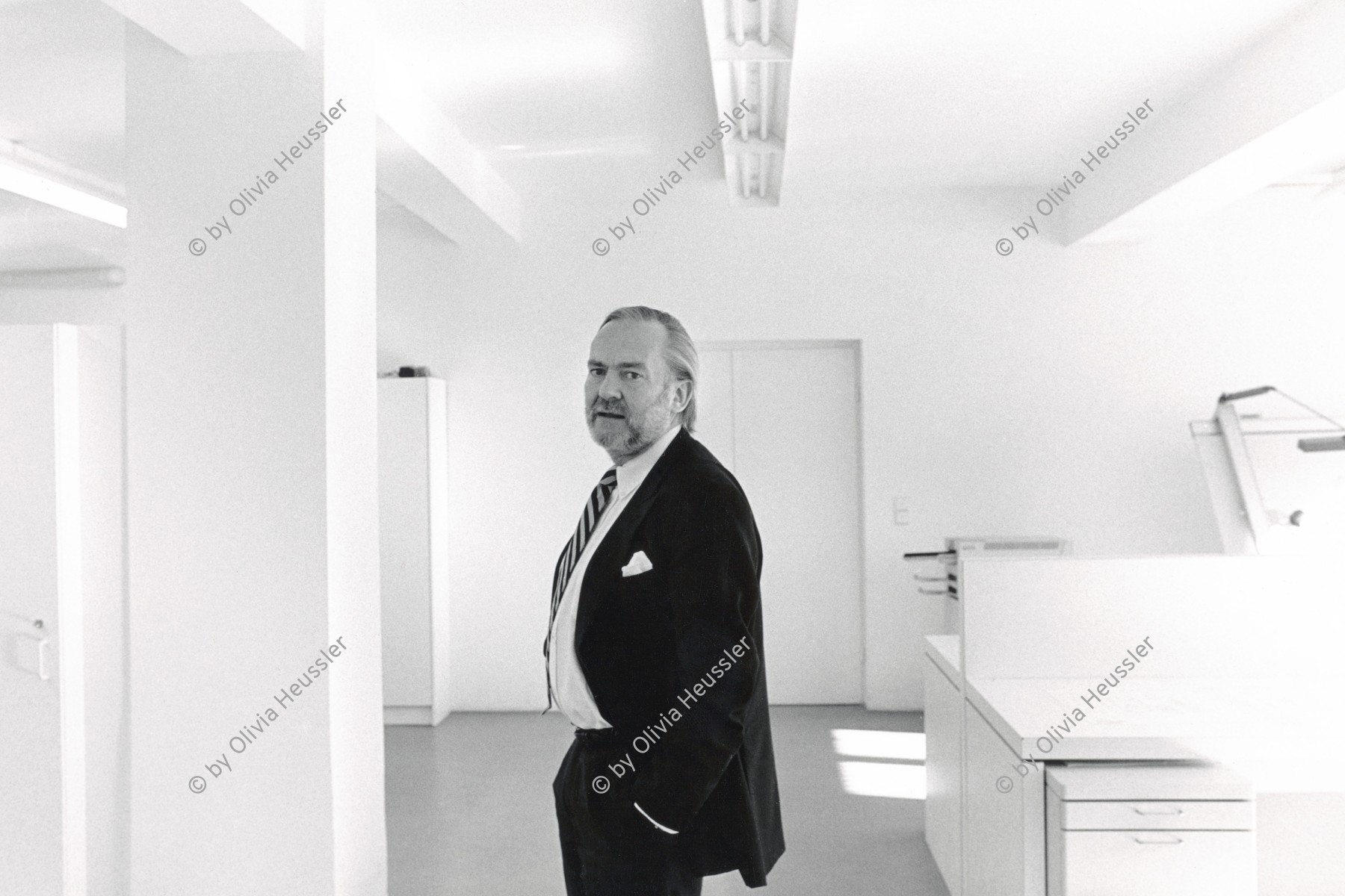 Image of sheet 19900080 photo 6: Deutscher Siemens Designer Herbert Schultes in seinem Atelier und Büro in München und vor seinen Olymp Leuchten und anderen von ihm designten Objekte. Hochparterre 
Herbert H. Schultes (* 1938) München Deutschland 1990 √