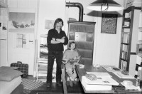 Image of sheet 19900110 photo 1: Portrait vor Ofen im Erismannhof. Städtische Siedlung Zürich 
Iris Zoe und Ruedi Teklenburg. Carla Lia Monti 'Räuberinnen' Ofen Erismannhof 2. Kindergarten. Kinder spielen mit Gewehren. Achmed von Warthburg. Fahrrad in der Stube. X liegt auf Sofa. Carla Lia Monti beim Haareschneiden. Sadam Hussein auf Poster. Zürich 1990